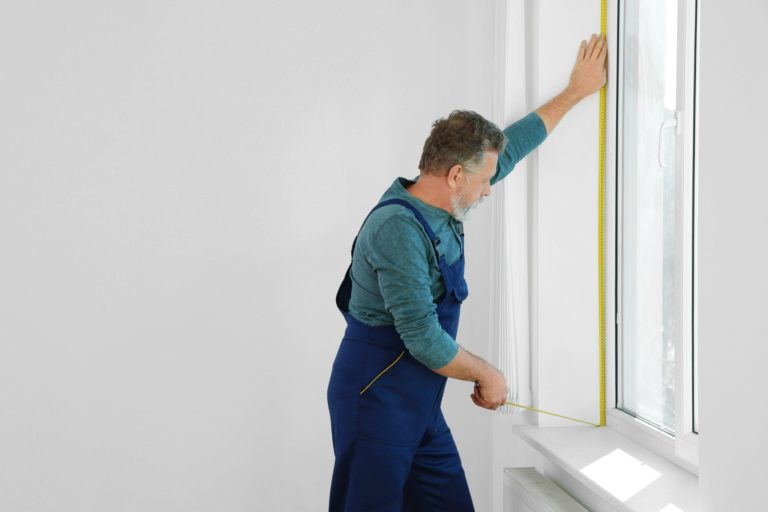 Service man measuring window for installation indoors
